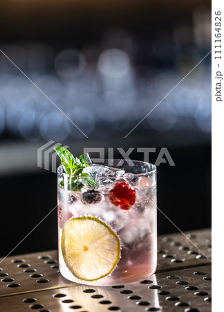 Pink cocktail Gin Tonic drink with raspberries, blueberries, lime and fresh mint Pink cocktail Gin Tonic drink with raspberries, blueberries, lime and fresh mint 111164826
