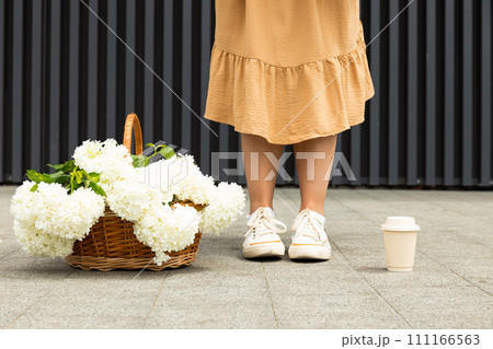 Girl with flowers and coffee, on the street in summer. 111166563