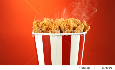 Fried Chicken Pieces in Paper Bucket, Isolated on Colored Background. Concept of Junk Food. Fried Chicken Pieces in Paper Bucket, Isolated on Colored Background. Concept of Junk Food. 111167649