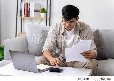 Man is calculating annual tax with calculator and filling form of Individual Income Tax Return. Season to pay Tax and Budget planning concept. 111168108