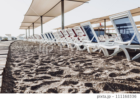 Mediterranean Sea, sandy beach with pebbles and palm trees. relaxation area with sun loungers by the sea. 111168336