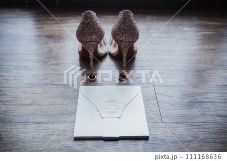 shoes of the bride with wedding rings on the floor 111168636