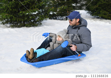 A father with child sledding in the snow 111168816