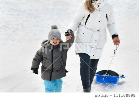 A mother with son sledding in the snow A mother with son sledding in the snow 111168999