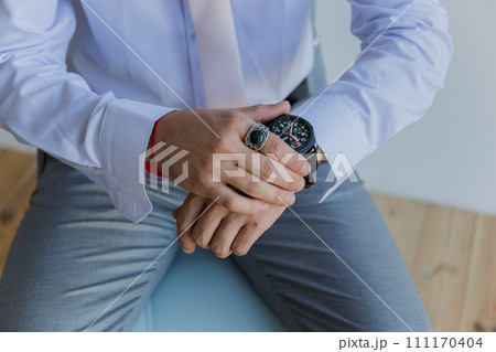 a man in a shirt puts a watch on his hand 111170404