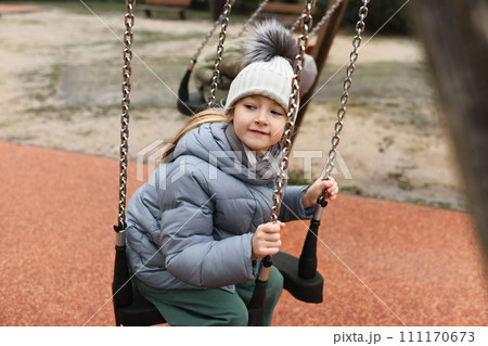 Girl six years old riding on a swing Girl six years old riding on a swing 111170673