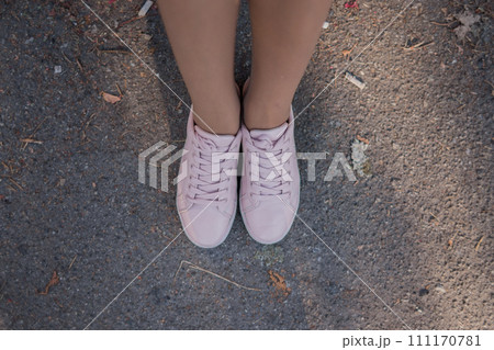 legs in pink sneakers on the pavement 111170781