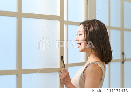 窓際で日差しを浴びる女性 111171458