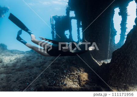 Attractive woman freediver swims underwater among the ruins of a ship. Freediving at wreck ship 111171956