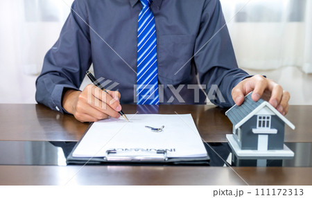 Real estate agents hand holding pen, home model, explains the business contract for signing a business contract, renting, buying, mortgage, loan or home insurance Real estate agents hand holding pen, home model, explains the business contract for signing a business contract, renting, buying, mortgage, loan or home insurance 111172313
