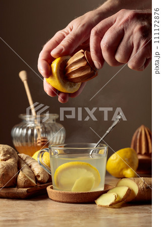 Ginger tea with lemon and honey on a brown ceramic table. 111172876
