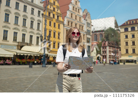 Fantastic view of the ancient homes on a sunny day. Woman with city map and smart phone. Gorgeous and picturesque scene. Location famous Market Square in Wroclaw, Poland, Europe. Historical capital of 111175326