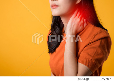 Young asian woman 30s wearing orange shirt holding her pain neck isolated on yellow background. office syndrome health care concept. 111175767
