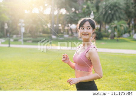 Experience the joy of wellness living as a happy, beautiful Asian woman in her 30s in a park at sunset. 111175984