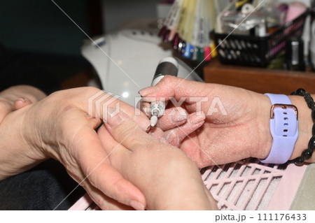 A manicurist works with a milling cutter. A manicurist works with a milling cutter. 111176433