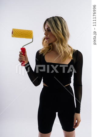 Young woman with roller brush on red white background Instruments accessories for renovation room Young woman with roller brush on red white background Instruments accessories for renovation room 111176996