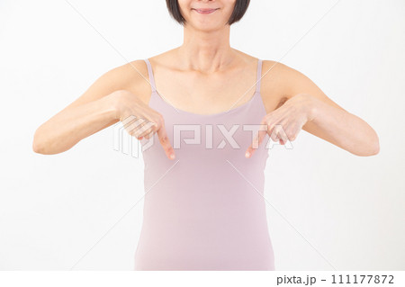 笑顔で下を指差すキャミソール姿のミドル女性 111177872