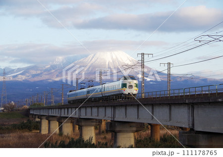 冠雪の大山を背景に日野川の長い鉄道橋梁を駆け抜ける復刻版みどりやくも色の381系特急やくも号 111178765