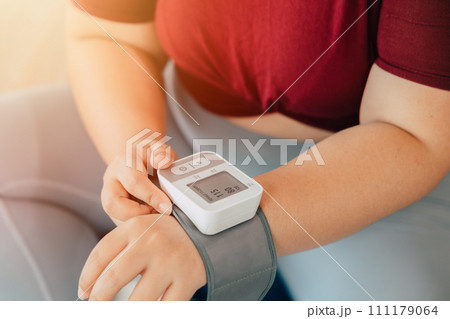 fat women measuring blood pressure using wrist blood vessels monitor modern home medical equipment fat women measuring blood pressure using wrist blood vessels monitor modern home medical equipment 111179064