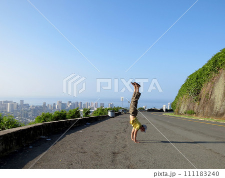 Man Handstands at Mountain lookout point above the City of Honolulu Man Handstands at Mountain lookout point above the City of Honolulu 111183240