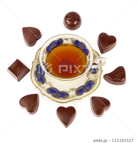 Tea in a porcelain vintage cup and chocolates isolated on a white. 111183327