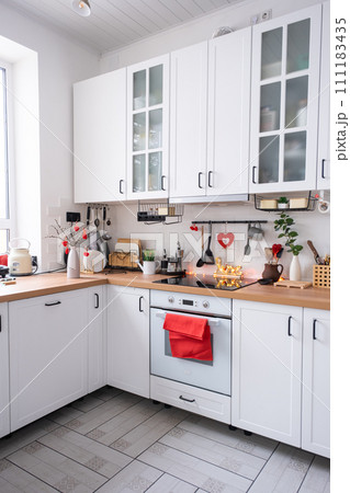 The interior of the kitchen in the house is decorated with red hearts for Valentine's Day. Decor on the table, stove, utensils, festive mood in a family nest The interior of the kitchen in the house is decorated with red hearts for Valentine's Day. Decor on the table, stove, utensils, festive mood in a family nest 111183435