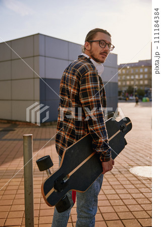 Hipster man wearing casual attire walking with skateboard 111184384