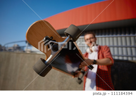 Hipster guy holding wooden skateboard for extreme race, hobby concept 111184394