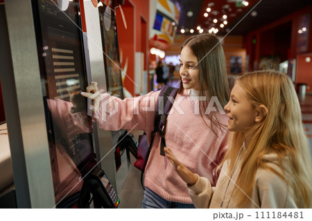 Two preteen girls using modern self-service kiosk at shopping mall Two preteen girls using modern self-service kiosk at shopping mall 111184481