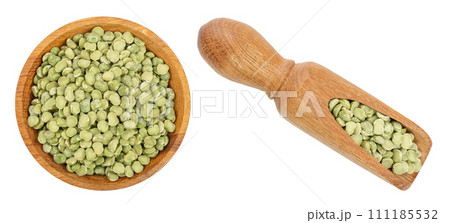 Green split peas in a wooden bowl and scoop isolated on white background. Top view Green split peas in a wooden bowl and scoop isolated on white background. Top view 111185532