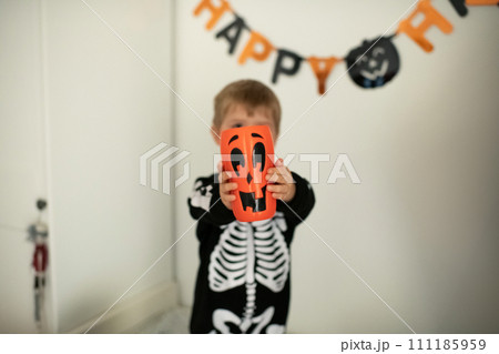 Boy in a skeleton costume and a pumpkin in his hands 111185959