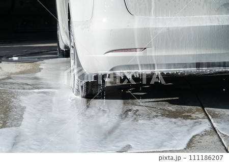 Efficiently cleaning an electric car in the comfort of a suburban driveway, combining eco-consciousness with practicality. 111186207