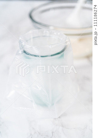 Transferring homemade royal icing into the piping bags for decorating sugar cookies. Transferring homemade royal icing into the piping bags for decorating sugar cookies. 111186274