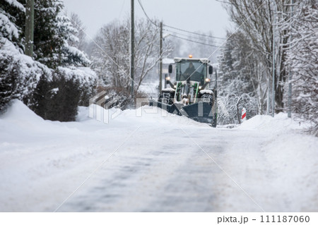 Tractor clears snow on road after heavy snowfall, road maintenance in winter season, harsh weather Tractor clears snow on road after heavy snowfall, road maintenance in winter season, harsh weather 111187060