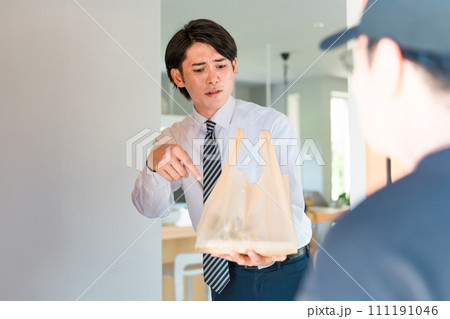 ウーバーイーツ・宅配弁当・デリバリー・配達・宅食・仕出し弁当の宅配のトラブルで怒る男性と配達員 111191046