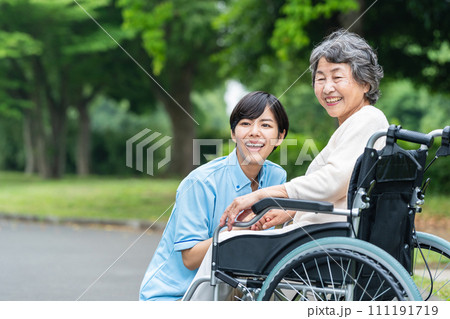 車椅子の高齢者と若い介護士 車椅子の高齢者と若い介護士 111191719
