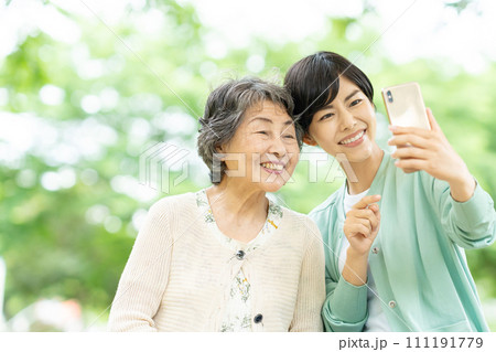 スマートフォンで自撮りするシニア女性と若い女性 111191779