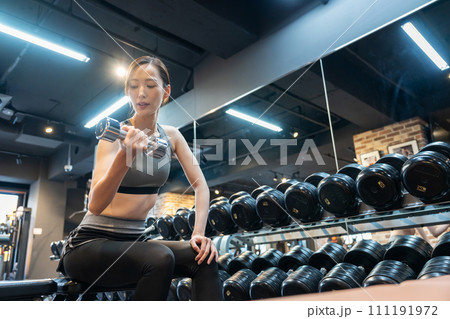 ジムで筋トレをする若い女性 111191972
