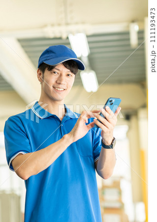 倉庫でスマホを使うドライバーの男性 111193473