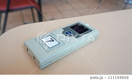 フードコートのテーブルに置かれた呼出ブザー フードコートのテーブルに置かれた呼出ブザー 111194608