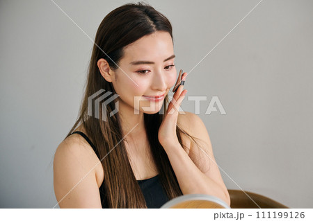 ファンデーションを塗るロングヘアの30代女性 111199126