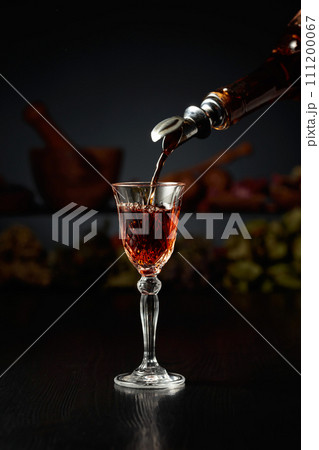 Brown herbal liquor or rum is poured from a vintage bottle. Brown herbal liquor or rum is poured from a vintage bottle. 111200067