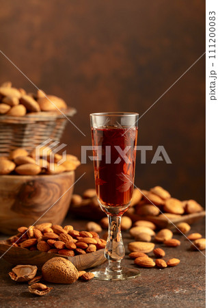 Italian liqueur Amaretto with almonds nuts on a brown background. 111200083