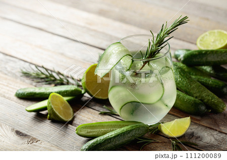 Gin tonic with ice, rosemary, lime, and cucumber on an old wooden table. Gin tonic with ice, rosemary, lime, and cucumber on an old wooden table. 111200089