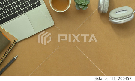 Laptop, cup of coffee, notepad and headphone on brown background. Top view with copy space 111200457