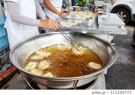 Hawker deep frying the Ham Chim Peng in wok with hot oil, a popular Chinese street food in Malaysia Hawker deep frying the Ham Chim Peng in wok with hot oil, a popular Chinese street food in Malaysia 111200771