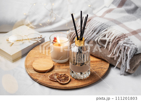 Home fragrance in glass bottle and bamboo sticks with scented candle, paper book. Home fragrance in glass bottle and bamboo sticks with scented candle, paper book. 111201803