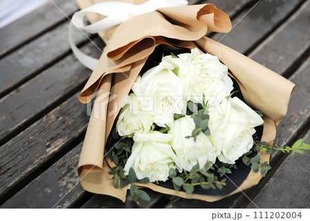 White roses bouquet on old wood background. 111202004