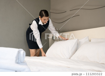Hotel room service. Young woman maid making bed in guest room. Hotel room service. Young woman maid making bed in guest room. 111203322