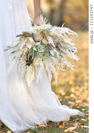 hands of the bride holding beautiful autumn bouquet outdoor 111203747